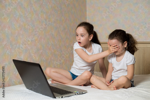 Little girl protects his sister from watching inappropriate content while using a computer. Internet safety for kids concept.