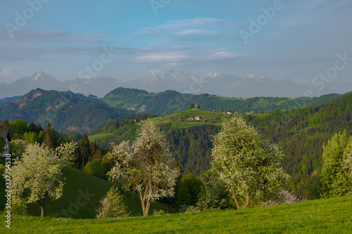 Slovenian breathtaking landscape with Julian Alps and charming little church of Sveti Tomaz (Saint Thomas) on a hill. Beautiful spring in the mountains, in Slovenia.