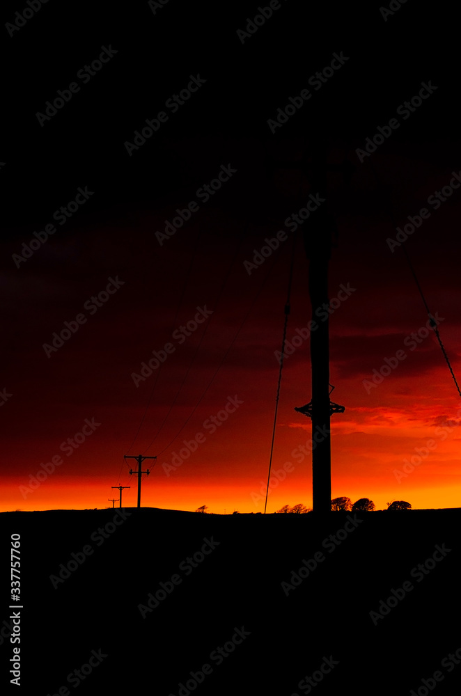 Orange hue sunset with telephone poles