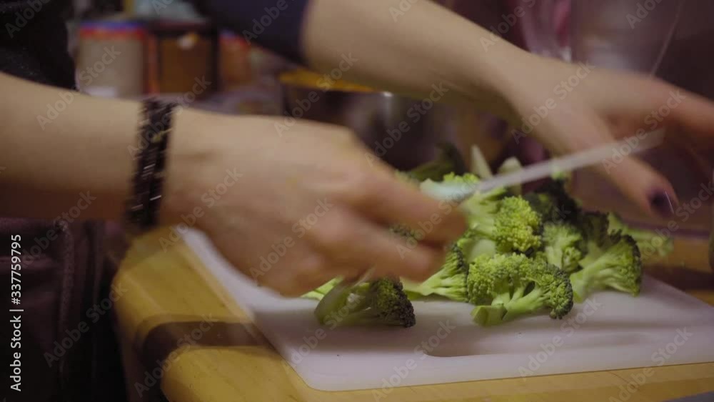 Girl cutting vegetables broccoli in the kitchen on white board Girl cutting vegetables broccoli in the kitchen on white board