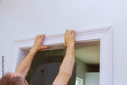 Construction handyman installing the interior door molding of apartment