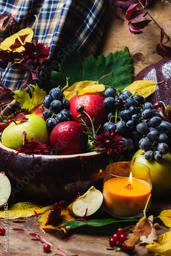 autumn fruits, apples, grapes and autumn leaves on a wooden background