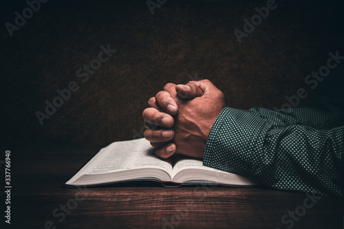Hands of a man praying over an open bible photo