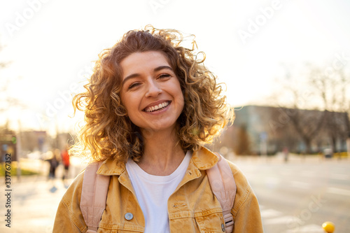 Portrait of young woman with curly hair in the city 