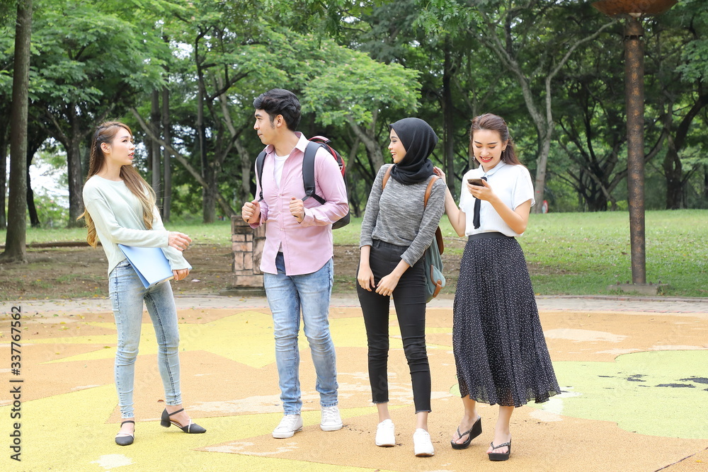 Young asian malay chinese man woman outdoor park walk stand study talk discuss point laptop file book backpack Young asian malay chinese man woman outdoor park walk stand study talk discuss point laptop file book backpack