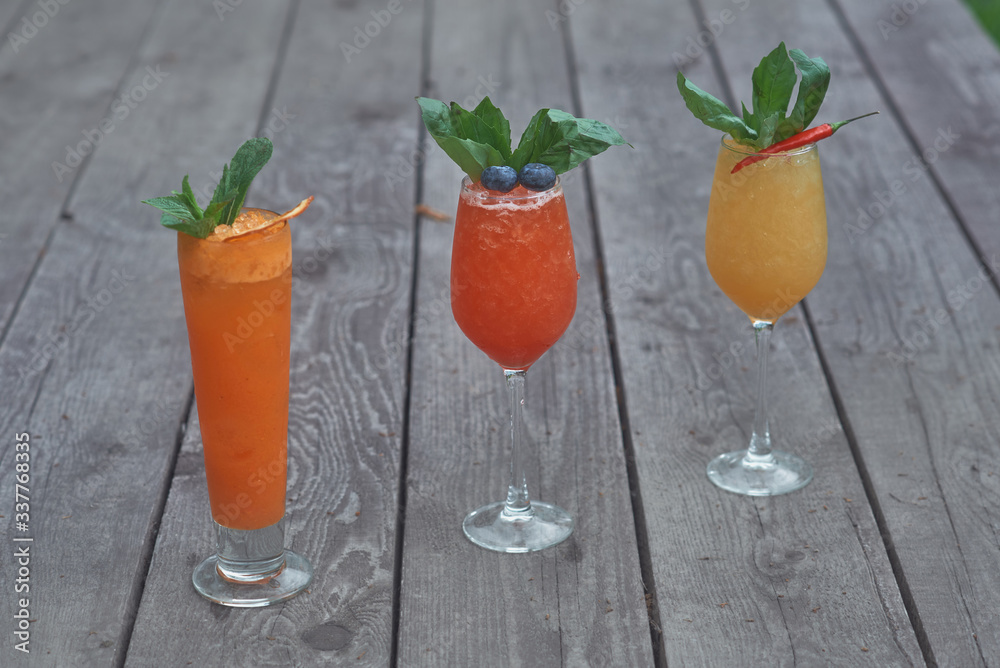 Fototapeta premium three alcoholic cocktails with fruits on an old wooden table