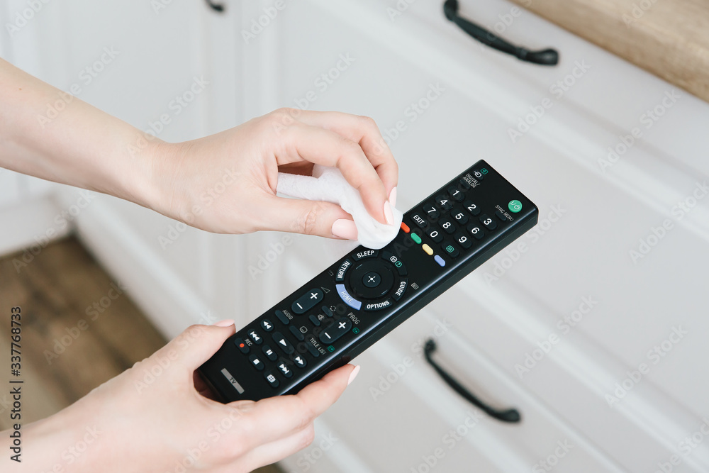 Female hands close-up, clean the TV remote control from dirt. Prevention of influenza and Covid-19. Female hands close-up, clean the TV remote control from dirt. Prevention of influenza and Covid-19.