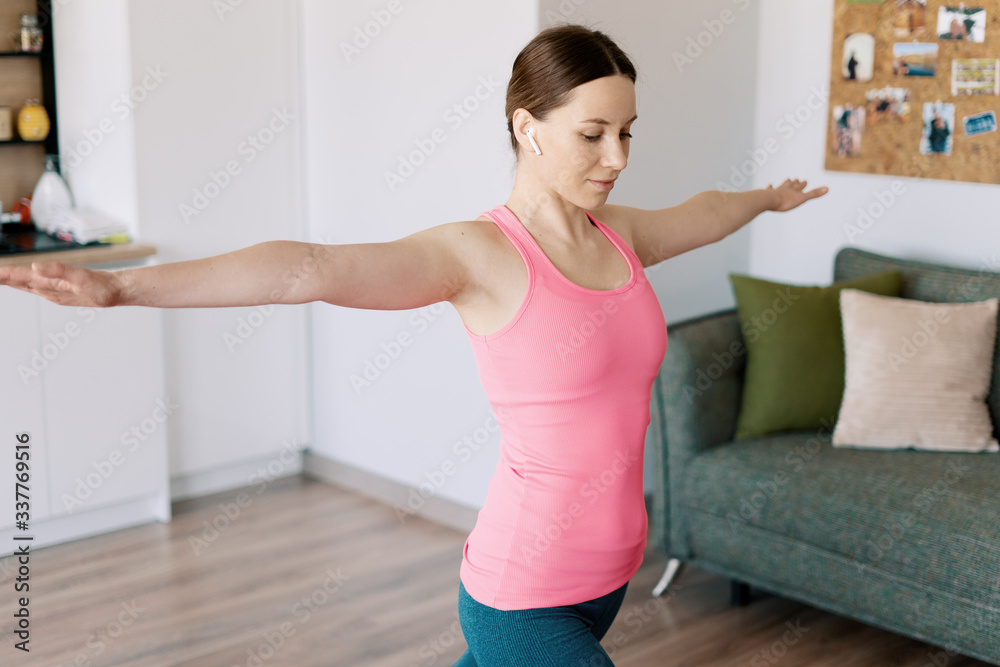 Attractive woman practicing yoga at home using online training instructions