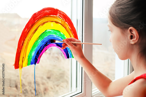 Schoolgirl draws rainbow sign of hope on window photo