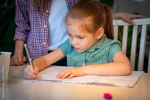 Φωτογραφία older sister helps younger with lessons at home.