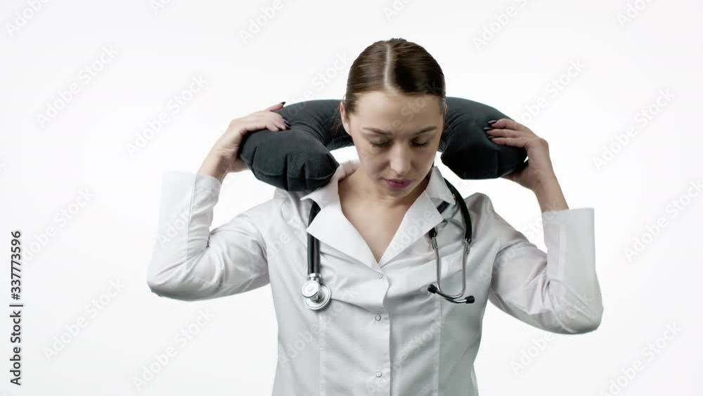 Young beautiful female doctor in medical uniform feels tired, yawns, put on portable travel neck pillow for nap or snooze and closed her eyes, isolated white background. Overworking, medical concept Young beautiful female doctor in medical uniform feels tired, yawns, put on portable travel neck pillow for nap or snooze and closed her eyes, isolated white background. Overworking, medical concept