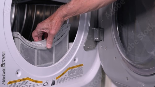 Senior caucasian man holding the lint filled trap from a front loading tumble dryer in 4K video
