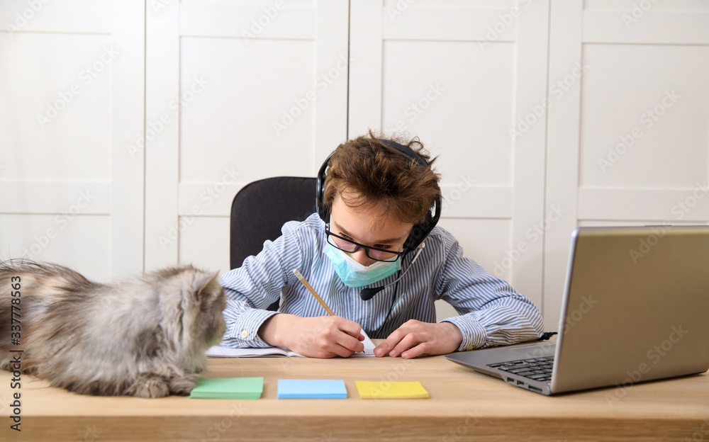 schoolboy in medical mask studying at home. Distance learning online education, coronavirus quarantine schoolboy in medical mask studying at home. Distance learning online education, coronavirus quarantine