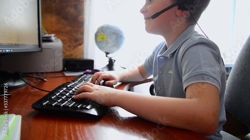 The boy is working at a computer on the table at home, distance learning photo