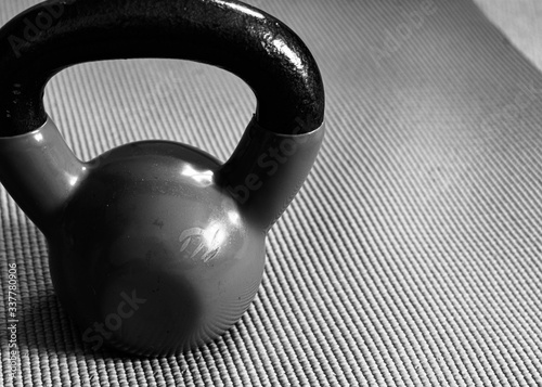 Fototapeta Naklejka Na Ścianę i Meble -  Black and white photo of a well used kettlebell weight on top of a yoga mat