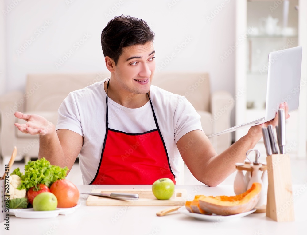 Man with laptop preparing food at the kitchen Man with laptop preparing food at the kitchen