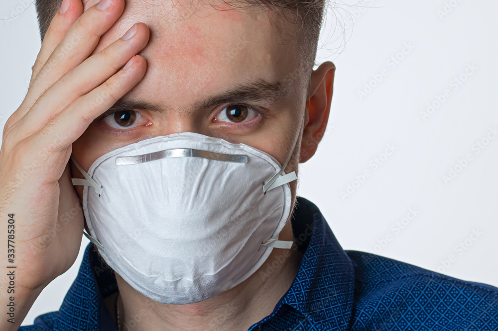 Young man wearing a protective mask against coronavirus, and various infections- quarantine, disease on a white background Young man wearing a protective mask against coronavirus, and various infections- quarantine, disease on a white background
