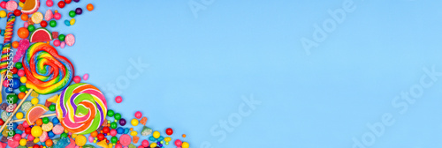 Colorful assortment of candies. Above view corner border with a blue banner background.
