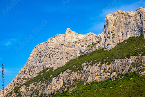 Panoramic view of cliffs and slopes of main limestone massif, Monte Cannone peak, of Isola Tavolara island on Tyrrhenian Sea off northern coast of Sardinia, Italy