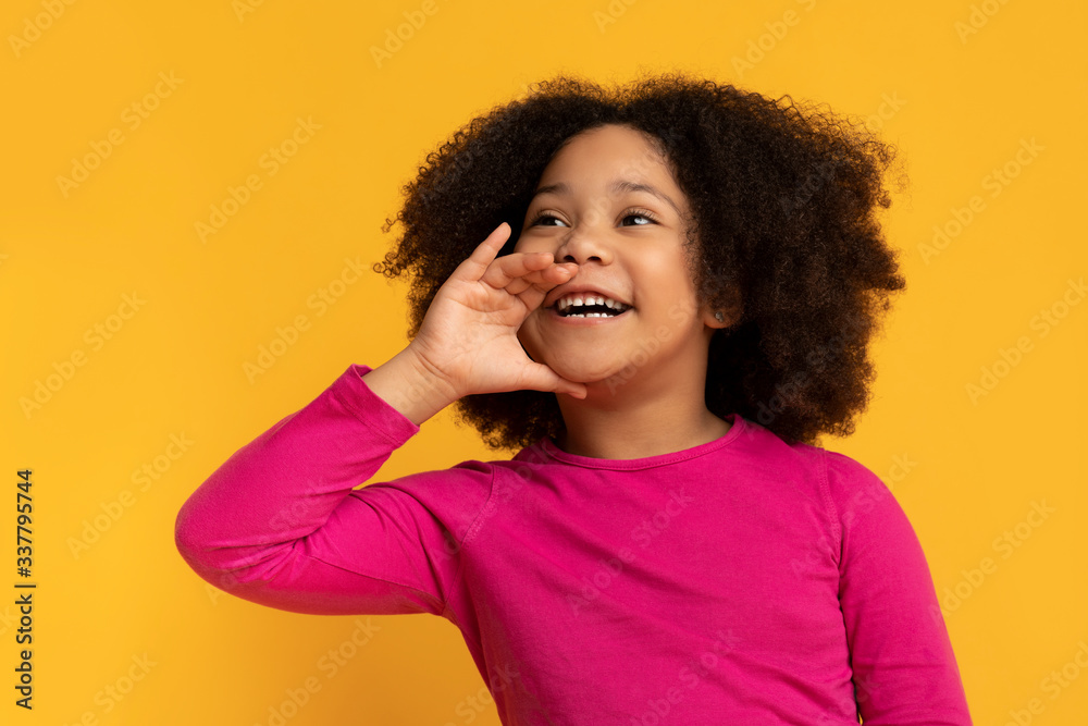 Overjoyed cute little black child holding hand near mouth, making announcement Overjoyed cute little black child holding hand near mouth, making announcement
