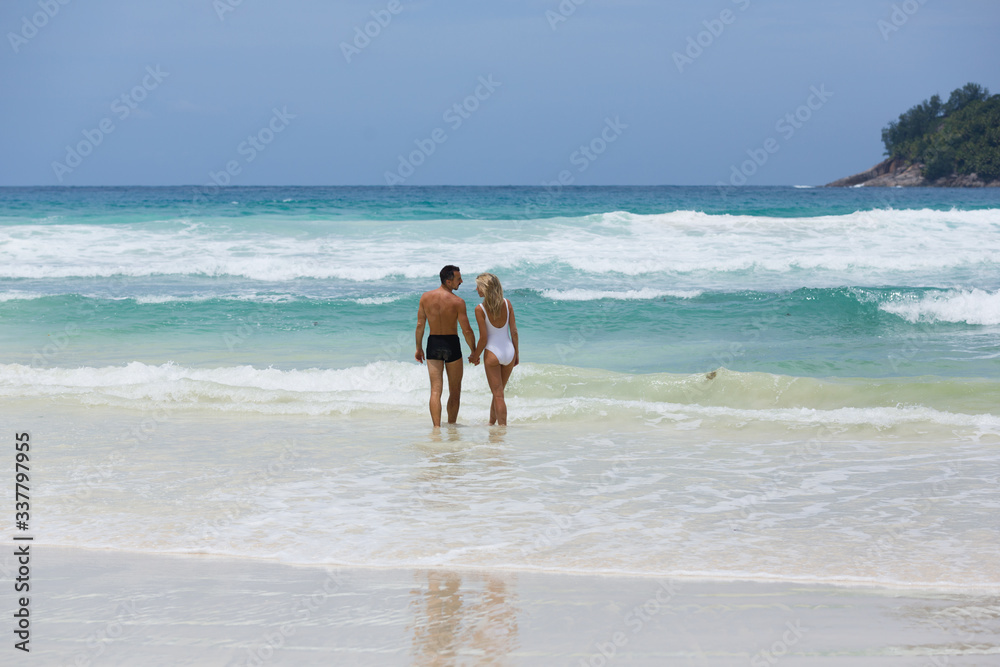 Beautiful loving married couple enjoy their vacation together at tropical beach in Seychelles.