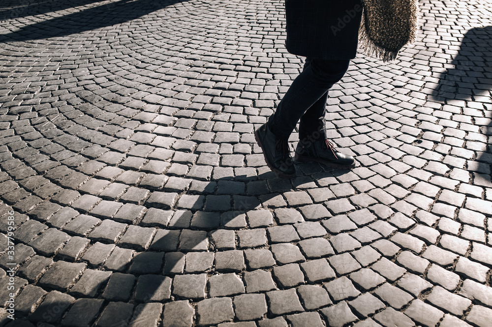 Women's legs in black jeans and winter boots walk along gray granite paving  stones and casts a contrasting shadow.. The concept of a walk in the old  city. Stock Photo | Adobe