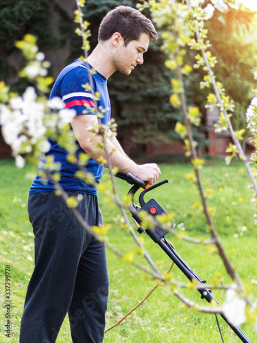 Young man using a lawn mower in his back yard