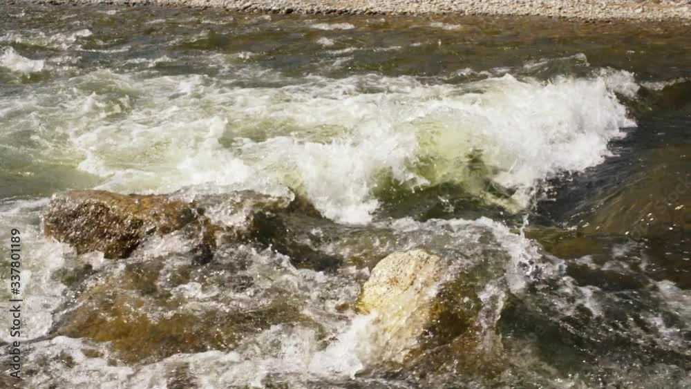 Spring river water flowing over sun lit rocks creating white waves, slow motion video Spring river water flowing over sun lit rocks creating white waves, slow motion video