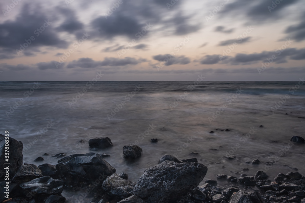 Naklejka premium Waves on the Atlantic Ocean at sunrise. Caleta de La Guirra Beach, Fuerteventura, Canary islands, Spain. October 2019. Long exposure shot.