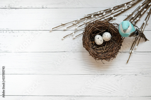 Easter background. Nest with easter eggs and decorative blue bird on wooden background. photo