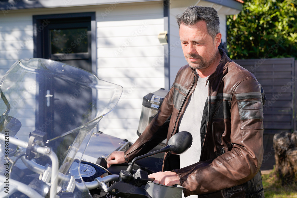 Handsome man with beard in brown leather biker jacket aside trail modern motorbike Handsome man with beard in brown leather biker jacket aside trail modern motorbike