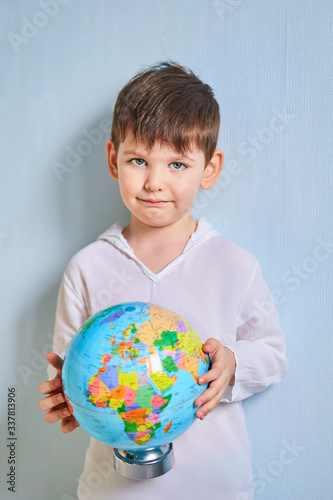 the globe in the hands of a boy on a blue background.coronavirus