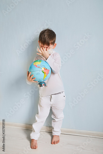 a globe in the hands of a boy on a blue background and a medical mask.coronavirus