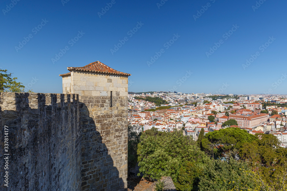 Surrounding wall of the historical Sao Jorge Castle (Saint George Castle, Castelo de Sao Jorge) and view of the Lisbon city in Portugal, on a sunny day in the summer.
