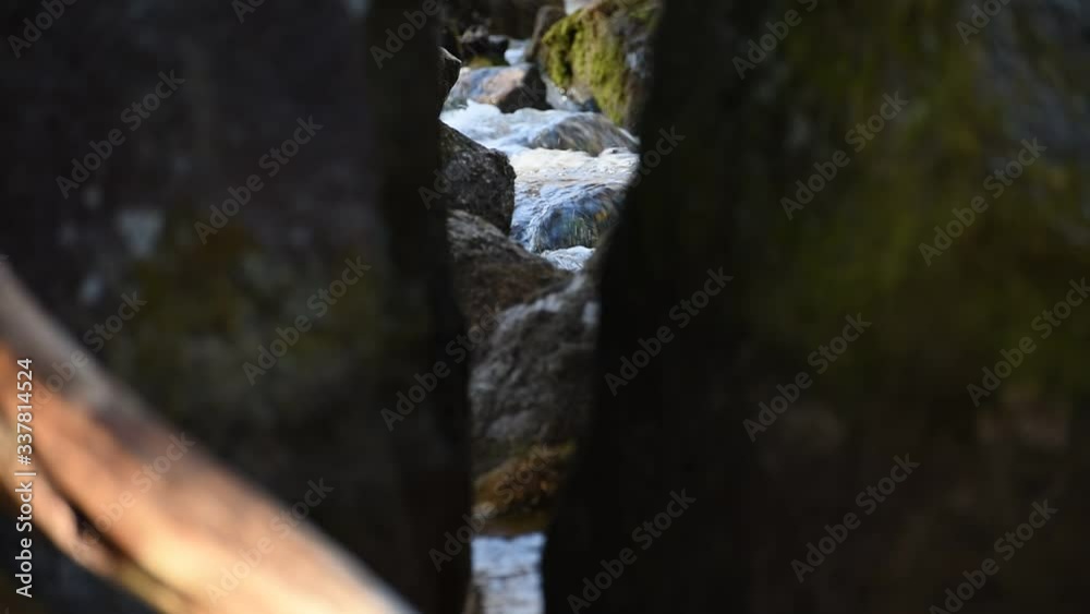 Rushing water with a view between a large rock that is divided in the middle of the Swedish valley during the spring. Rushing water with a view between a large rock that is divided in the middle of the Swedish valley during the spring.
