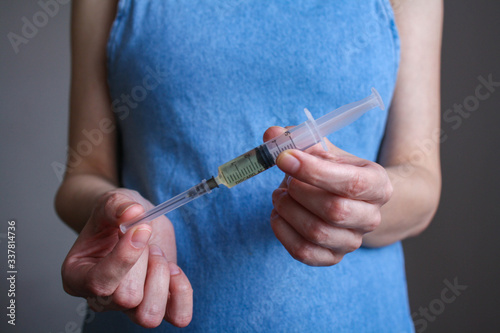 A young, pregnant woman holds a syringe in front of her © grankin_13d