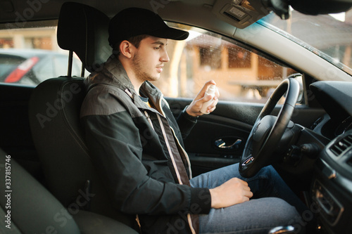 Man use disinfector in car. Handsome man protect himself and clean car inside using antiseptic