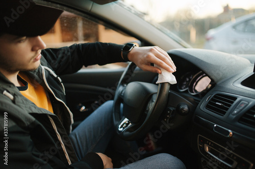 Man clean steering wheel using wet wipes. Man protect himself and clean car inside using antiseptic © Aleksandr