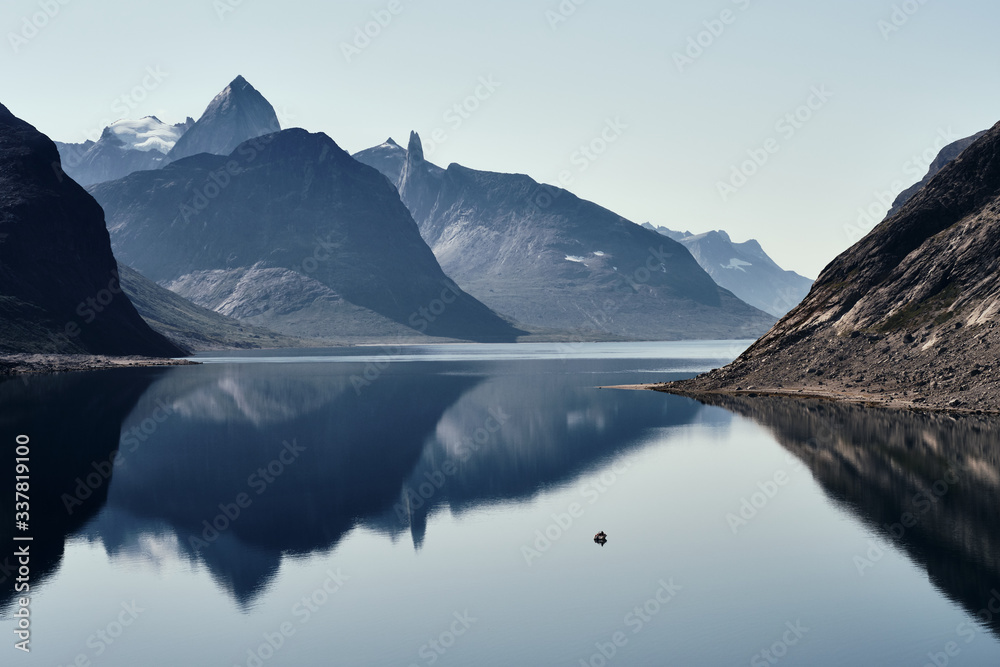 Landscape photo with mountains reflecting in the  fjord with a small boat 