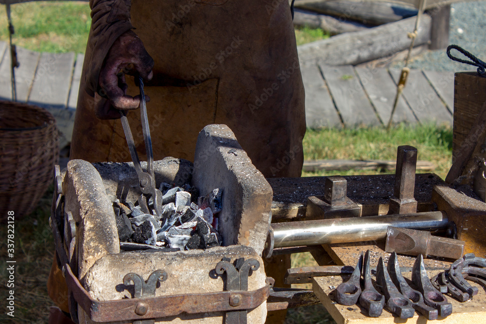 A blacksmith prepares coal for a medieval horn
