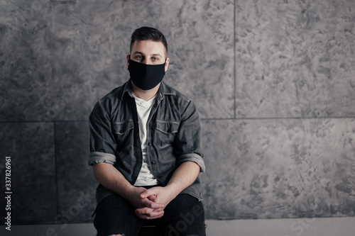 Young man with black mask in dark room pray for world and coronavirus quarantine