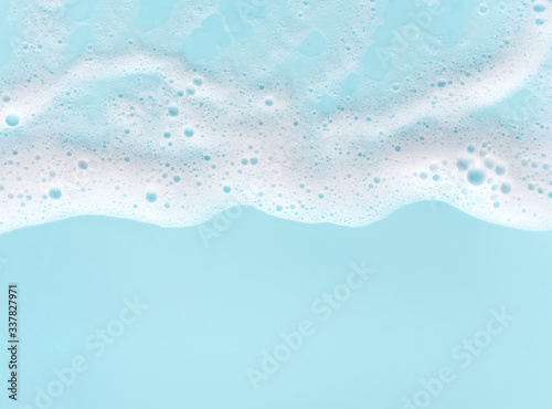 border of soap foam on turquoise background, with copy space photo
