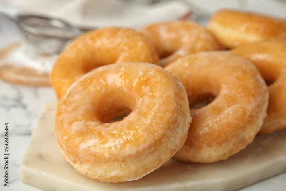 Sweet delicious glazed donuts on board, closeup