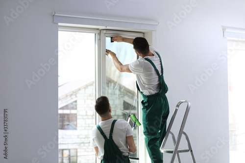 Professional workers tinting window with foil indoors © New Africa