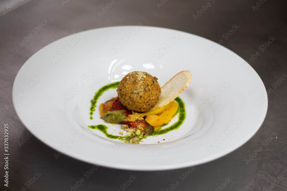 herb croquette of goat cheese with ragu of roasted peppers along with roasted pistachios