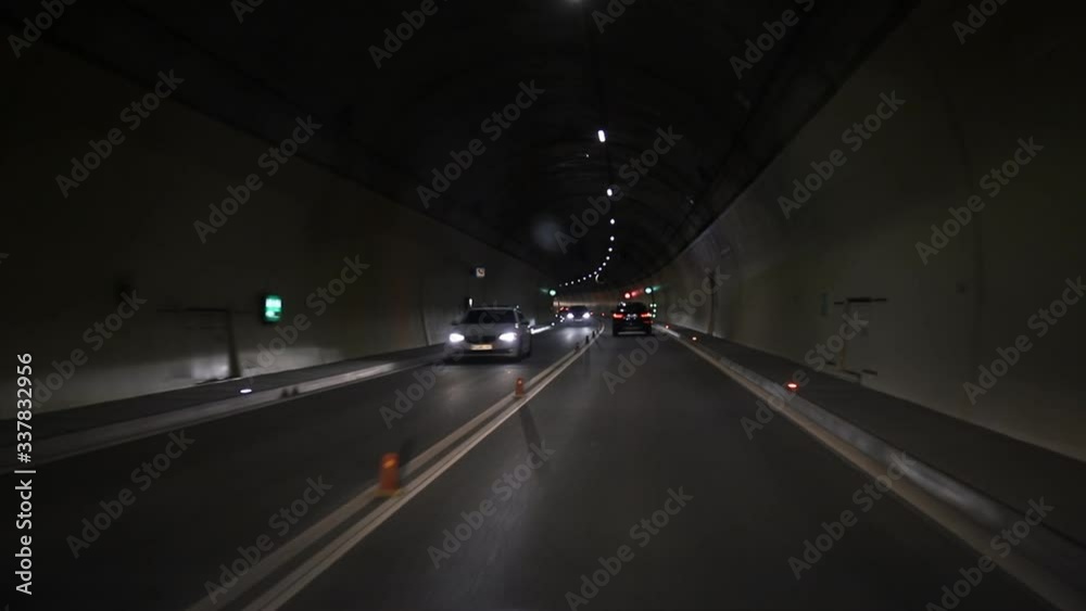 Automobile dark car tunnel with white arrows on asphalt showing way direction. Emergency exit sign with many lights. underground vehicle traffic road. Urban abstract city transportation background Automobile dark car tunnel with white arrows on asphalt showing way direction. Emergency exit sign with many lights. underground vehicle traffic road. Urban abstract city transportation background