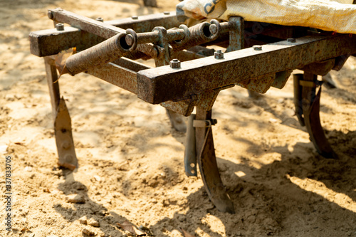 Close up of rusted plough on the back of a tractor digging into mud for crop planting