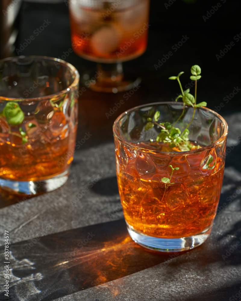 orange summer cocktail with ice on dark background. Shadows of glasses, hard sun light. orange summer cocktail with ice on dark background. Shadows of glasses, hard sun light.