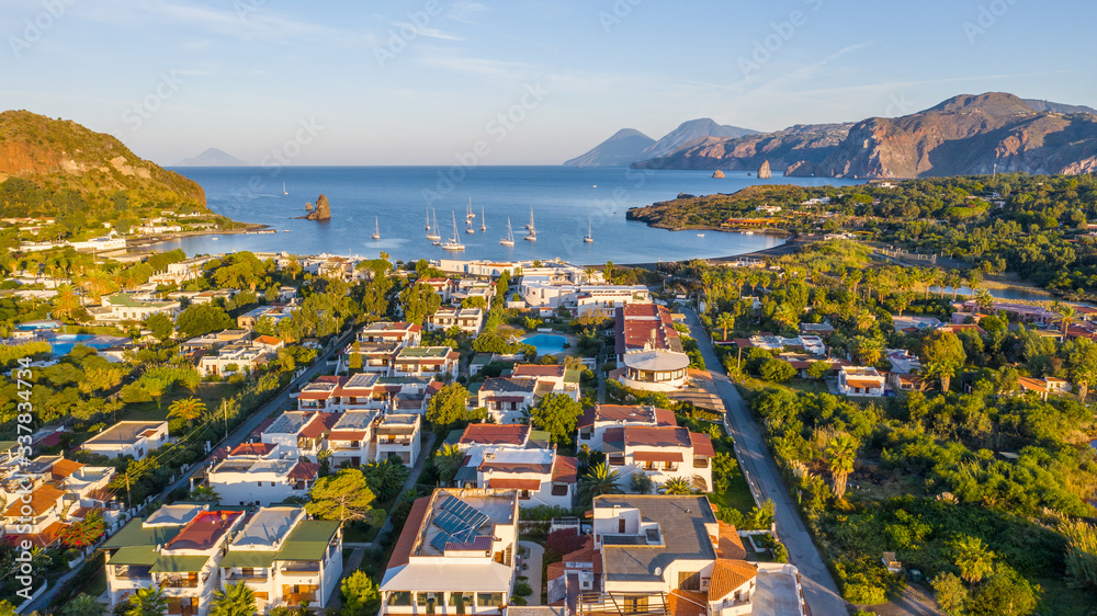 Aerial view photo from flying drone of The black sand beach with yachts in small haven in Porto di Ponente, in Vulcano, Italy on a summer at beautiful day with blue sky (series)