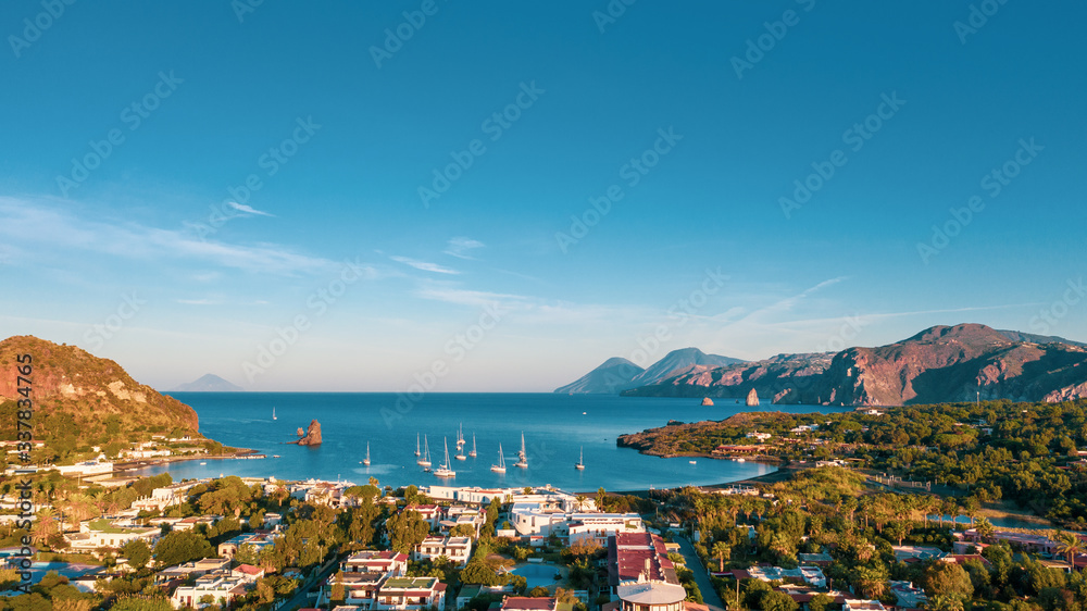 Aerial view photo from flying drone of The black sand beach with yachts in small haven in Porto di Ponente, in Vulcano, Italy on a summer at beautiful day with blue sky (series)